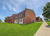 Thumbnail 11 of 29 - Liberty Plaza Townhome Building with blue skies overhead and green lawn in front.