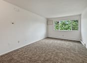 Thumbnail 9 of 10 - A room with a window and carpeted floor.