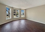 Thumbnail 5 of 15 - Empty room with wood flooring and three windows.