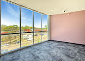 Thumbnail 19 of 20 - A room with a large window overlooking a parking lot and buildings.
