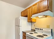 Thumbnail 4 of 10 - A white stove and refrigerator in a kitchen with wooden cabinets.