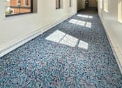 Thumbnail 15 of 20 - A long hallway with a blue carpet and white walls.