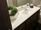 Thumbnail 23 of 31 - A bathroom with a white counter top and brown cabinets.