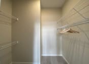 Thumbnail 25 of 31 - A walk in closet with white shelves and a light shining through the door.