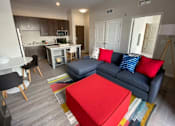 Thumbnail 31 of 31 - A living room with a blue couch and a red ottoman.