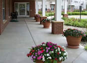 Thumbnail 1 of 16 - A porch with a brick wall and a white roof with flower pots on it.