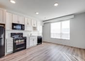 Thumbnail 24 of 37 - a kitchen with white cabinets and black appliances and a window