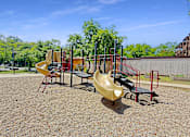 Thumbnail 4 of 15 - A playground with a yellow slide and red and black equipment.