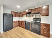 Thumbnail 11 of 19 - A kitchen with wooden cabinets and black appliances.