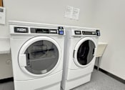 Thumbnail 12 of 19 - Two front loading washing machines in a laundry room.