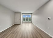 Thumbnail 15 of 19 - A room with a wooden floor and a sliding glass door leading to a balcony.