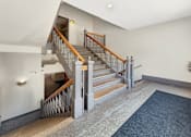 Thumbnail 18 of 20 - A staircase with a wooden handrail and a metal balustrade leads up to a landing with a door.