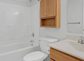 Thumbnail 16 of 27 - A white toilet in a bathroom with a wooden cabinet above it.