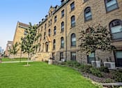 Thumbnail 3 of 27 - A large grassy area in front of a brick building.