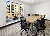 Thumbnail 2 of 43 - A conference room at The Harken with a table and chairs and a view of a street outside.