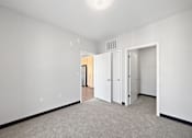 Thumbnail 4 of 43 - A white room with a carpeted floor and two doors.