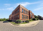 Thumbnail 2 of 20 - A red brick building with a black fence in front.