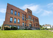 Thumbnail 1 of 20 - A red brick building with a tower and arched doorway.