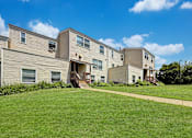 Thumbnail 1 of 28 - A row of houses with a green lawn in front.