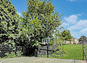 Thumbnail 28 of 28 - A basketball court surrounded by trees and a fence.