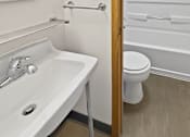 Thumbnail 29 of 29 - A white sink with a silver faucet and a toilet in a bathroom.