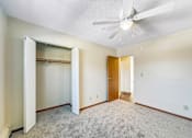 Thumbnail 7 of 12 - A room with a ceiling fan and carpeted floor.