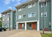 Thumbnail 2 of 10 - A green apartment building with a red door in the center.