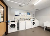 Thumbnail 33 of 35 - A laundry room with a row of washing machines