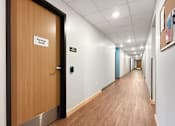 Thumbnail 27 of 35 - A long hallway with a wooden floor and a door at the end.