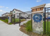Thumbnail 30 of 40 - the entrance to a building with a fence and a stone column with a blue logo