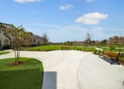 Thumbnail 34 of 40 - a park with benches and grass and houses in the background