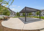 Thumbnail 35 of 40 - a park with a bench and a canopy in front of some apartments