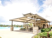 Thumbnail 18 of 40 - a pavilion with picnic tables and a pool in the background