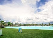 Thumbnail 15 of 40 - a lounge chair sits on the grass in front of a large blue pool with people in it