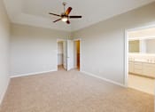 Thumbnail 12 of 17 - an empty living room with a ceiling fan and a bathroom
