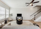 Thumbnail 7 of 17 - a living room with a couch and a tv in front of a staircase