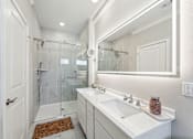 Thumbnail 10 of 17 - a white bathroom with a shower and a sink and a mirror