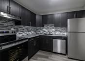 Thumbnail 15 of 20 - a black and white photo of a kitchen with black cabinets and stainless steel appliances