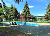 Thumbnail 11 of 12 - A pool surrounded by a fence with trees in the background.