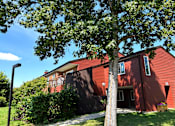 Thumbnail 9 of 12 - A red house with a tree in front.