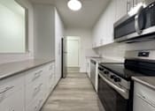 Thumbnail 7 of 12 - A modern kitchen with white cabinets and stainless steel appliances.