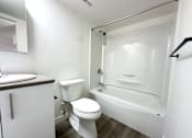 Thumbnail 5 of 12 - A white toilet sits next to a white bathtub in a small bathroom.