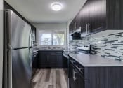 Thumbnail 11 of 16 - a kitchen with black cabinets and a stainless steel refrigerator
