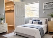 Thumbnail 5 of 14 - A bedroom with a bed, nightstand, and a window.
