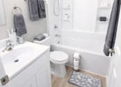 Thumbnail 7 of 12 - A white bathroom with a toilet, sink, and shower.