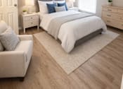 Thumbnail 4 of 10 - A bedroom with a large bed, a nightstand, a chair, and a rug.