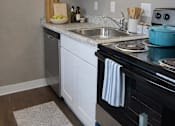 Thumbnail 2 of 14 - A kitchen with a black stove top oven and white cabinets.