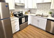 Thumbnail 17 of 26 - A kitchen with a stove, sink, and refrigerator.