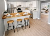 Thumbnail 1 of 26 - A kitchen with a bar stool and a counter with plates on it.