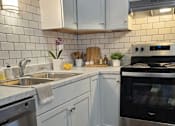 Thumbnail 18 of 26 - A kitchen with white cabinets and a stainless steel dishwasher.